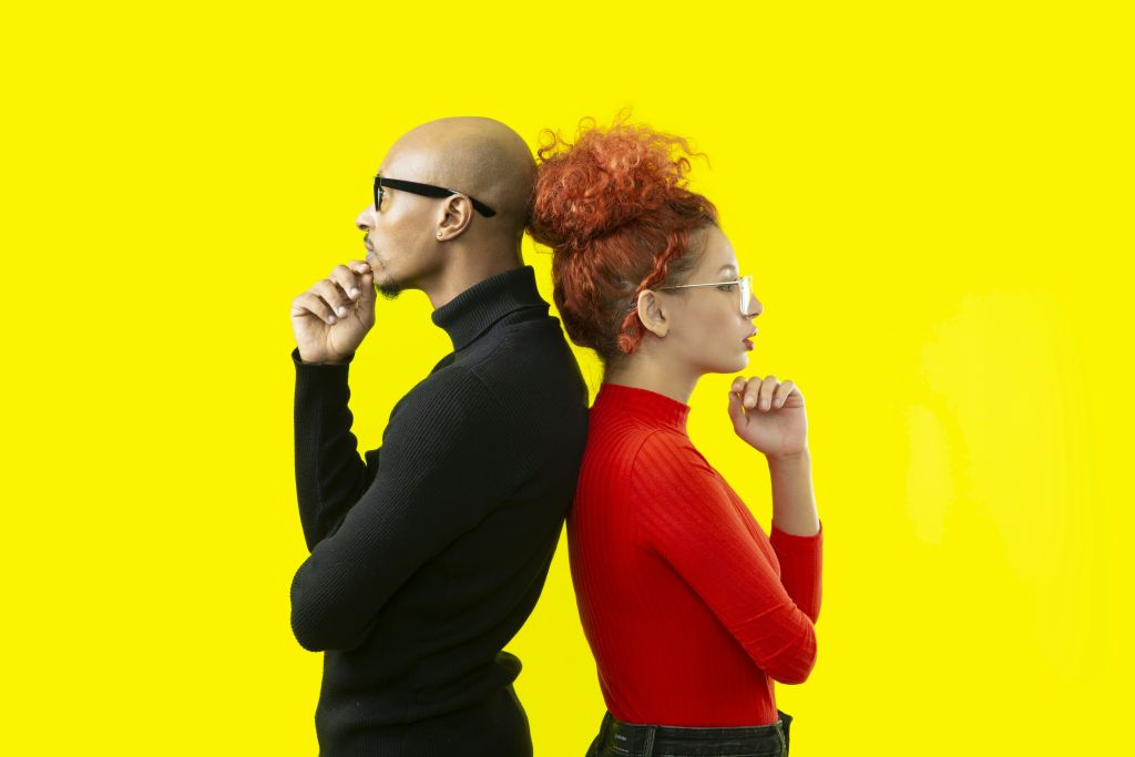 Two adults standing back to back, each looking in a different direction.