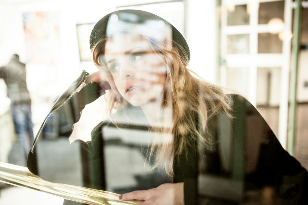 Woman resting her head on her hand while looking through a window.